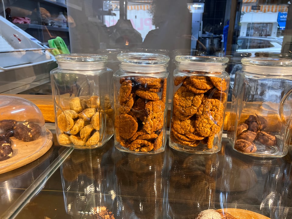 5 glass cannisters filled with different kinds of cookies on a glass shelf  