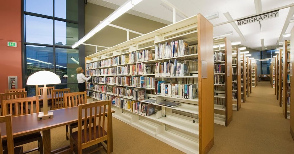 Image of the inside of a library. You can see library shelves and study tables.
