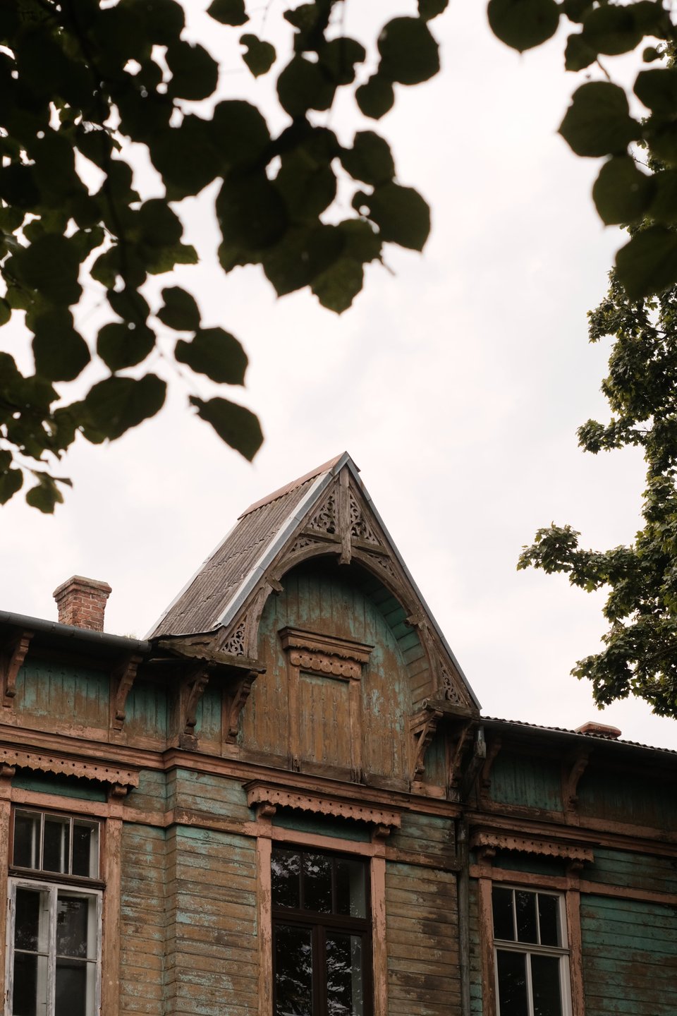 A photograph of an Art Nouveau wooden building, showcasing a decorative roof with a detailed woodcarved archway inside.