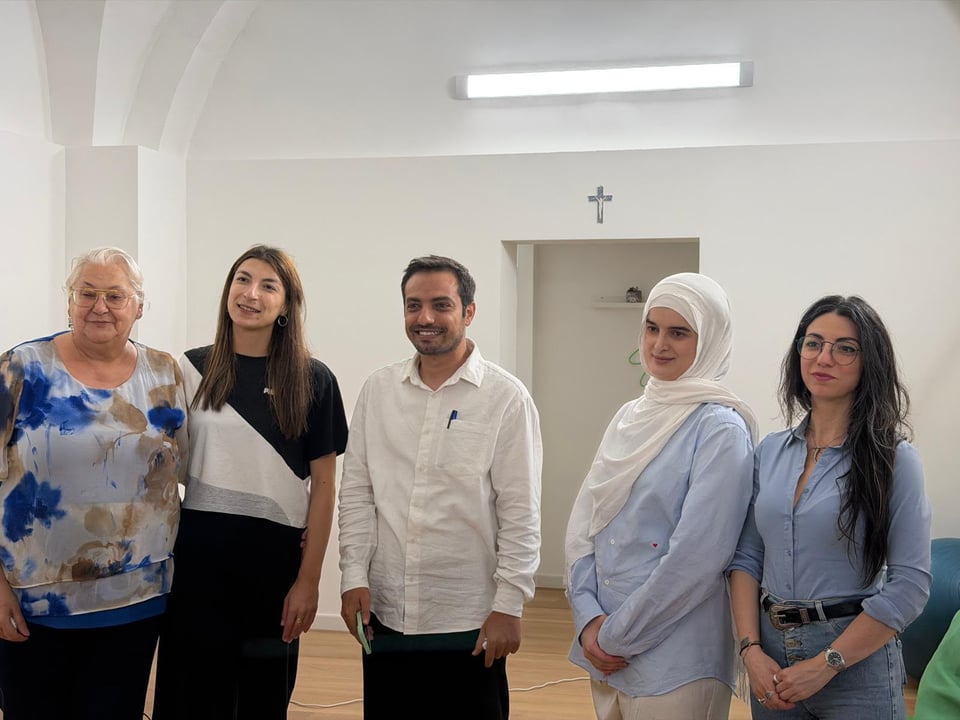 A photo of five people smiling for the camera, with Ahmed in the middle