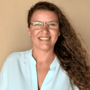 Picture of Saskia Franken, with long blonde curly hair and glasses, smiling into the camera.