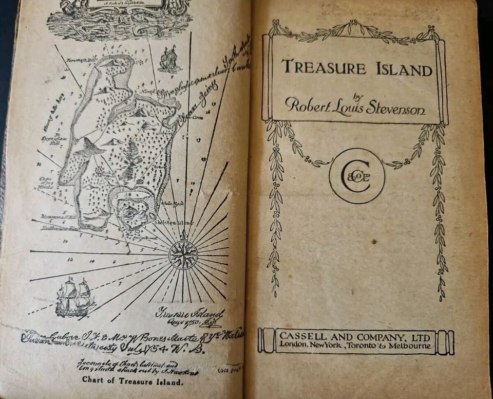 the inside pages of the book Treasure Island with a detailed map and a title