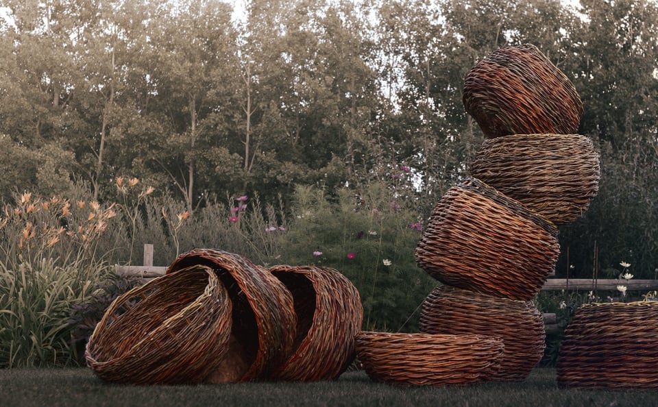 A tall stack of large twisted willow baskets made at Baskets in the Garden 2026