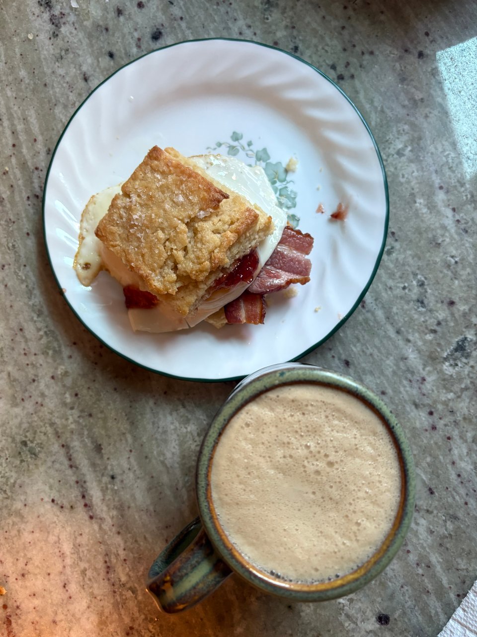 Top right - white plate containing a buttermilk sugar biscuit turned egg and bacon breakfast sandwich. Bottom right - gray-green mug filled with a creamy pine nut latte.