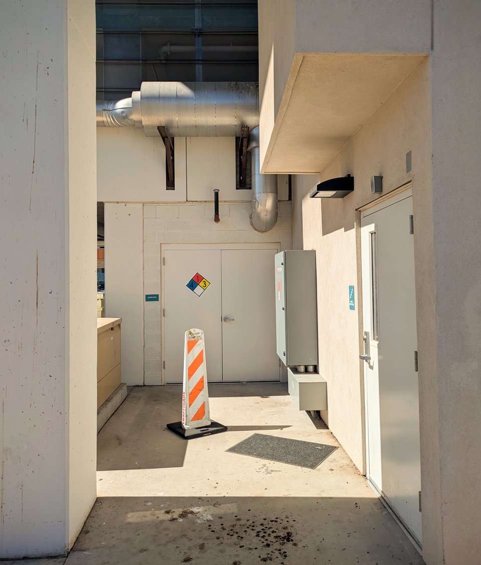 an obscure-looking corner outside a large building with several doors