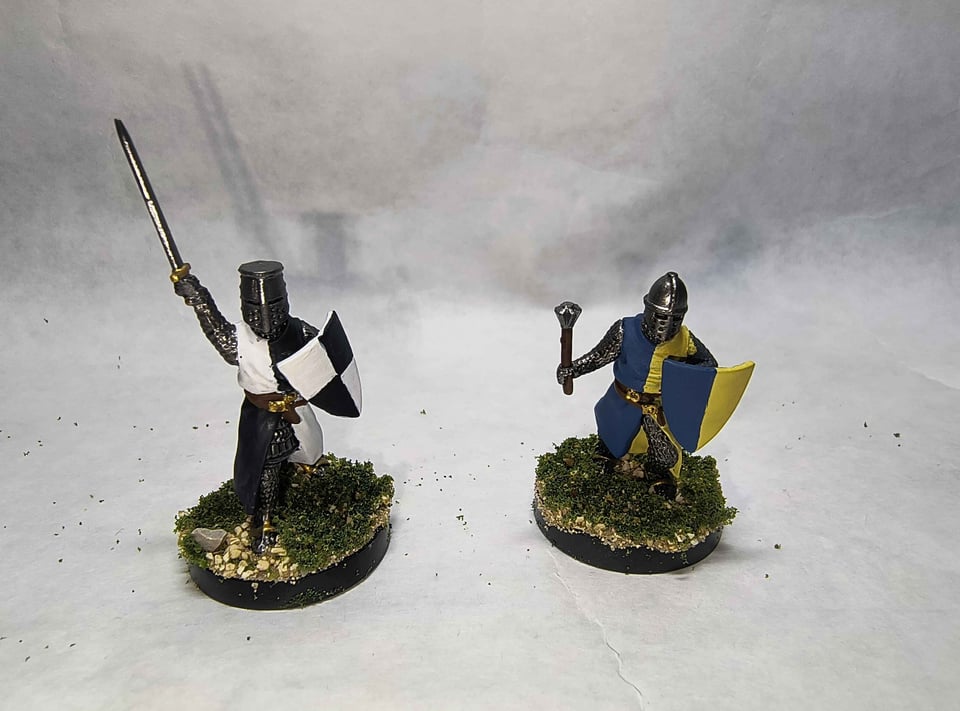 Two knights, one with a black and white surcoat, and one with a blue and yellow surcoat