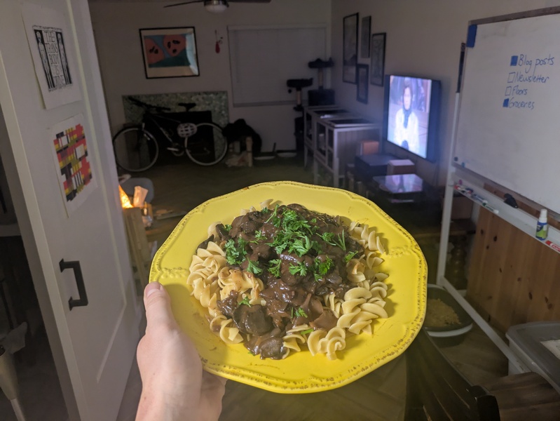 a plate of mushrooms and egg noodles in a thick, dark sauce topped with parsley