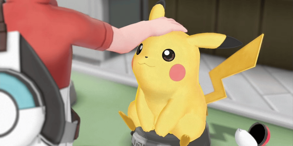 A person gently pats the head of a cheerful, cartoonish Pikachu sitting on a pedestal.