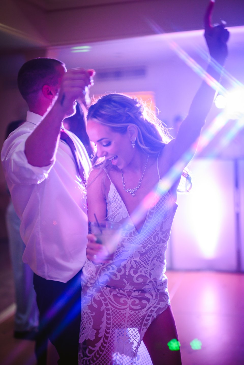 Bride and groom dancinging together to EDM with purple lights shining on them and featuring creative lens flare