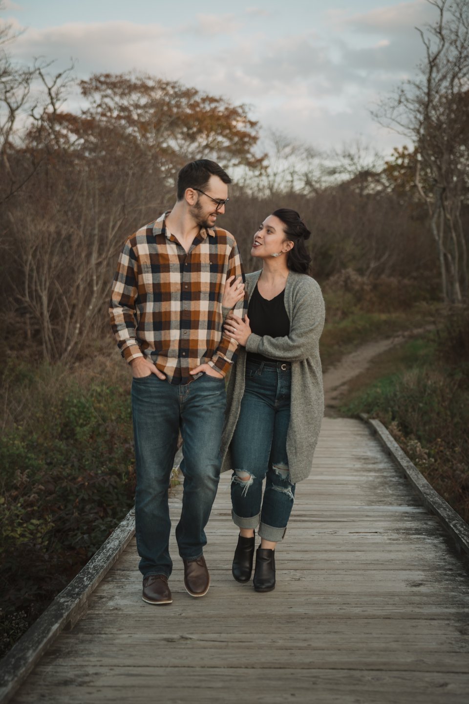 an engaged couple walking on a wooden boardwalk