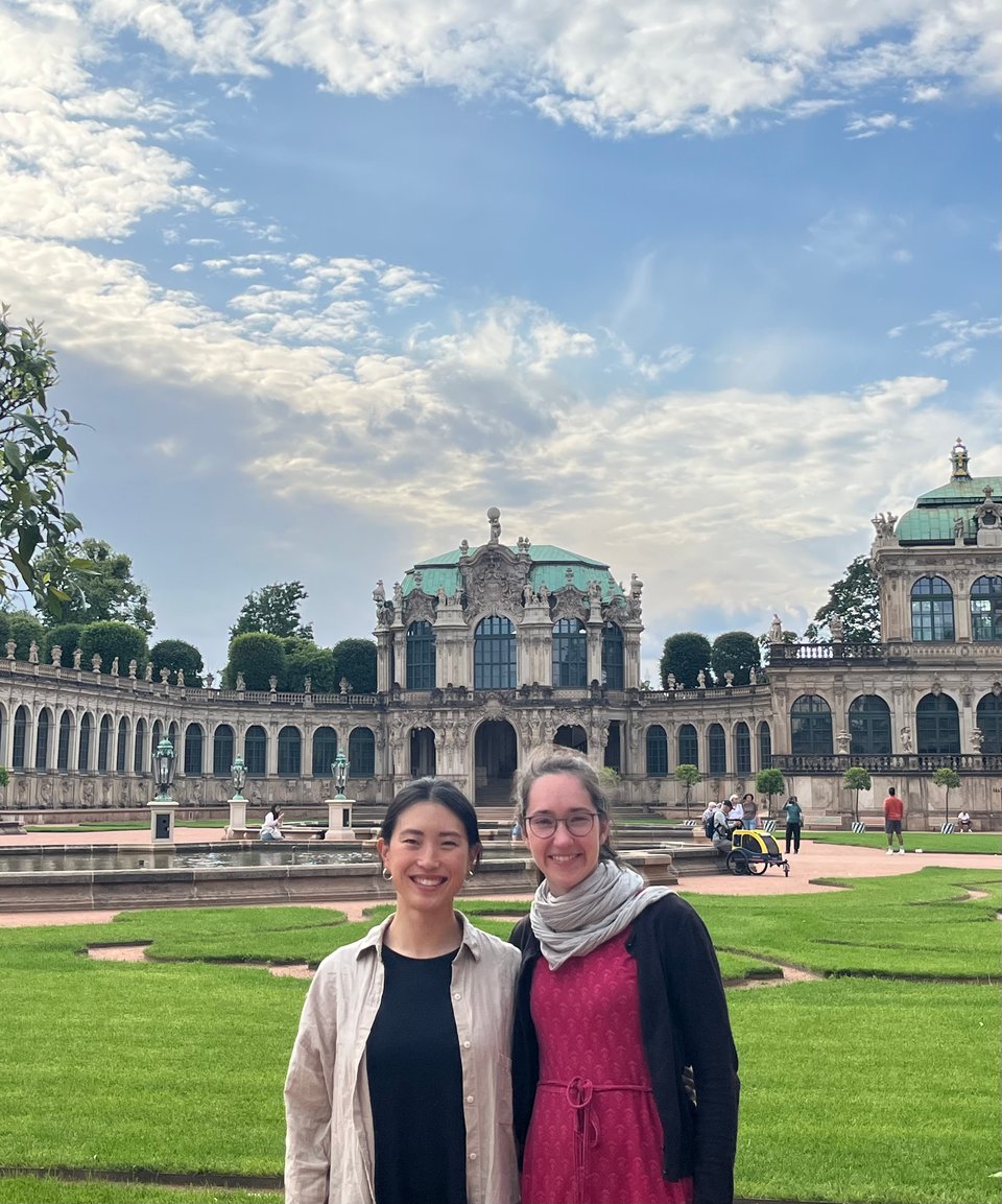 Jenny and Chrisi in front of palatial grounds and gardens smiling at camera