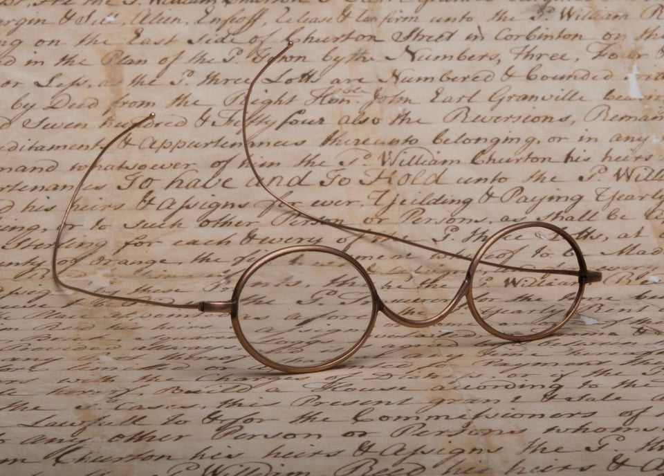 Gold-rimmed glasses lie on a handwritten letter.