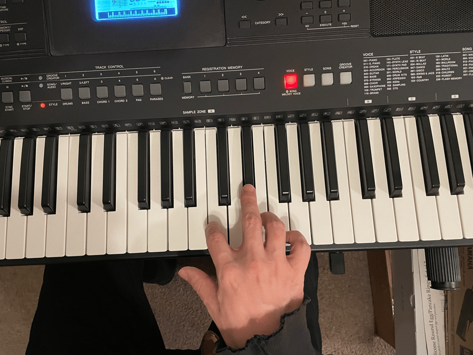 A person's hand on an electronic keyboard, plunking away