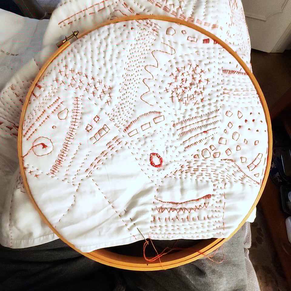 Detail of Red Map, a hand stitched quilt by Sarah Atlee, shown here in progress using a quilting hoop.
