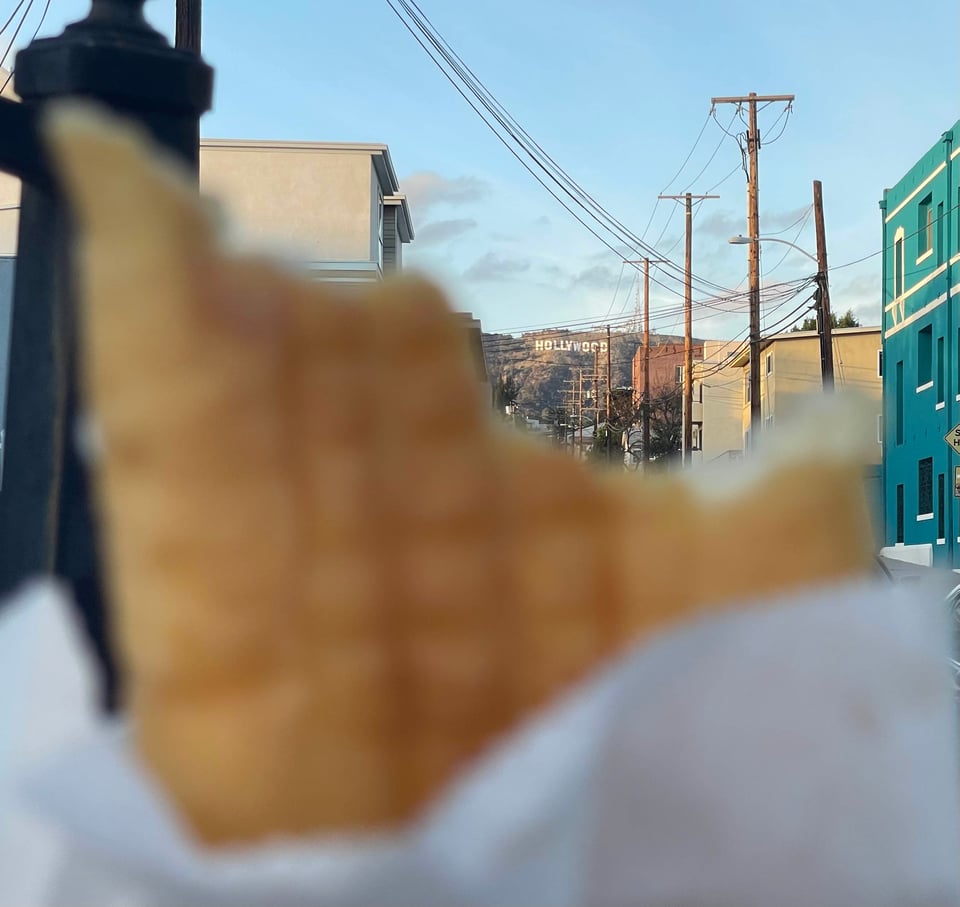 A blurry donut in the foreground, in the background the Hollywood Sign peeks above the donut