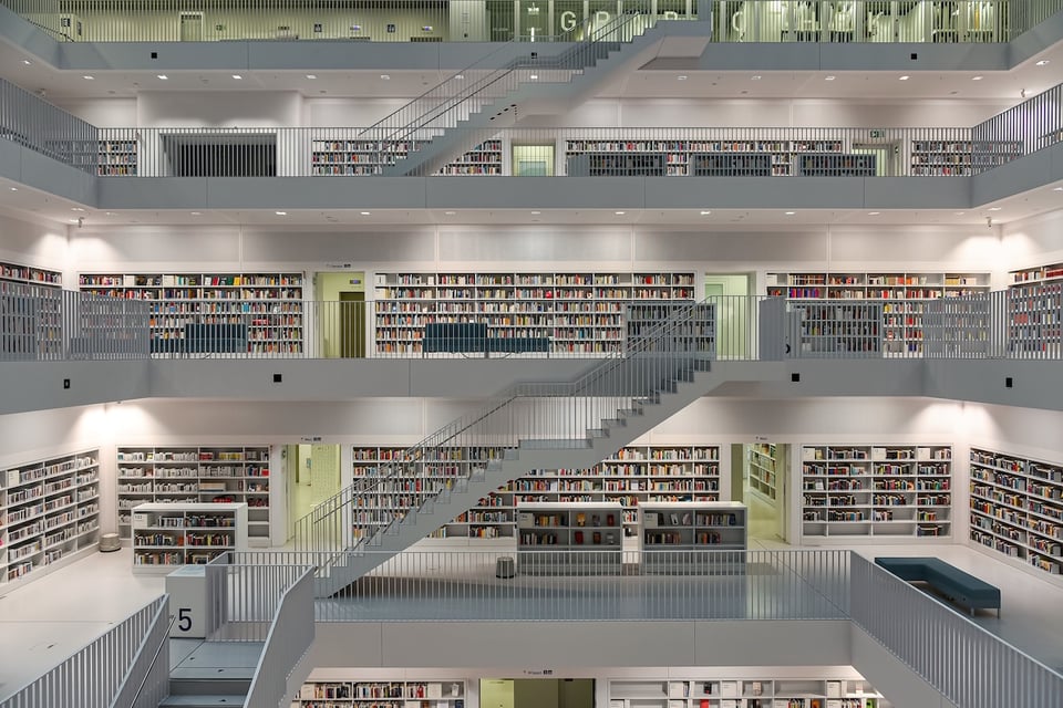 A multistory library connected by stairs, viewed in the evening from the atrium.