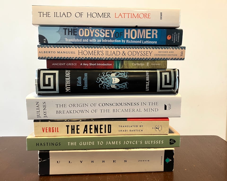 Stack of books:
- The Iliad, by Homer, translated by Richmond Lattimore
- The Odyssey, by Homer, also translated by Lattimore
- Homer’s the Iliad and the Odyssey: A Biography, by Alberto Manguel
- Ancient Greece: A Very Short Introduction, by Paul Cartledge
- Mythology, by Edith Hamilton
- The Origin of Consciousness in the Breakdown of the Bicameral Mind, by Julian Jaynes
- The Aeneid, by Virgil, translated by Shadi Bartsch
- The Guide to James Joyce’s Ulysses, by Patrick Hastings
- Ulysses, by James Joyce