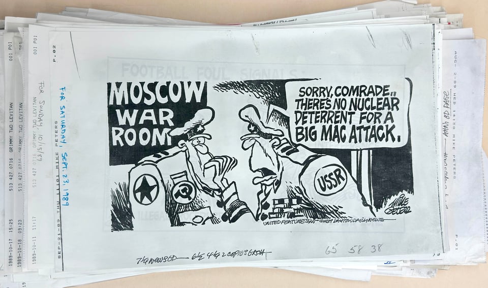 Stack of thermal fax sheets with one on top of a Sept. 23, 1989, cartoon by Mike Peters with two military figures talking to each other about a Big Mac attack