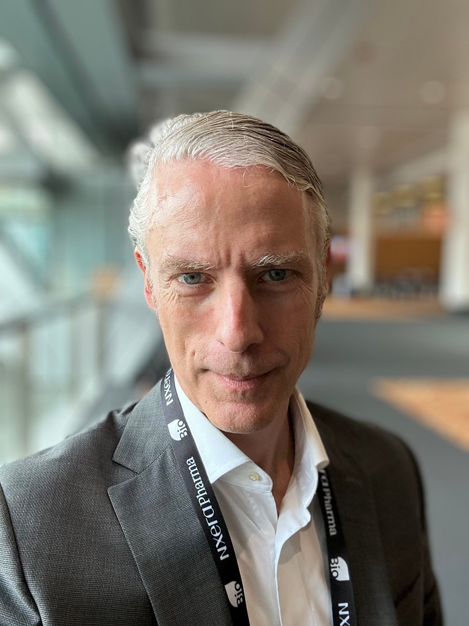 portrait-mode selfie of white man in gray suit and white dress shirt, with a black lanyard around his neck; he's got a slight smile and you probably want to open up to him about your midlife crisis.