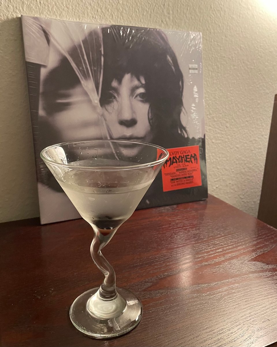 A martini in front of the Lady Gaga album, Mayhem, resting on a record player
