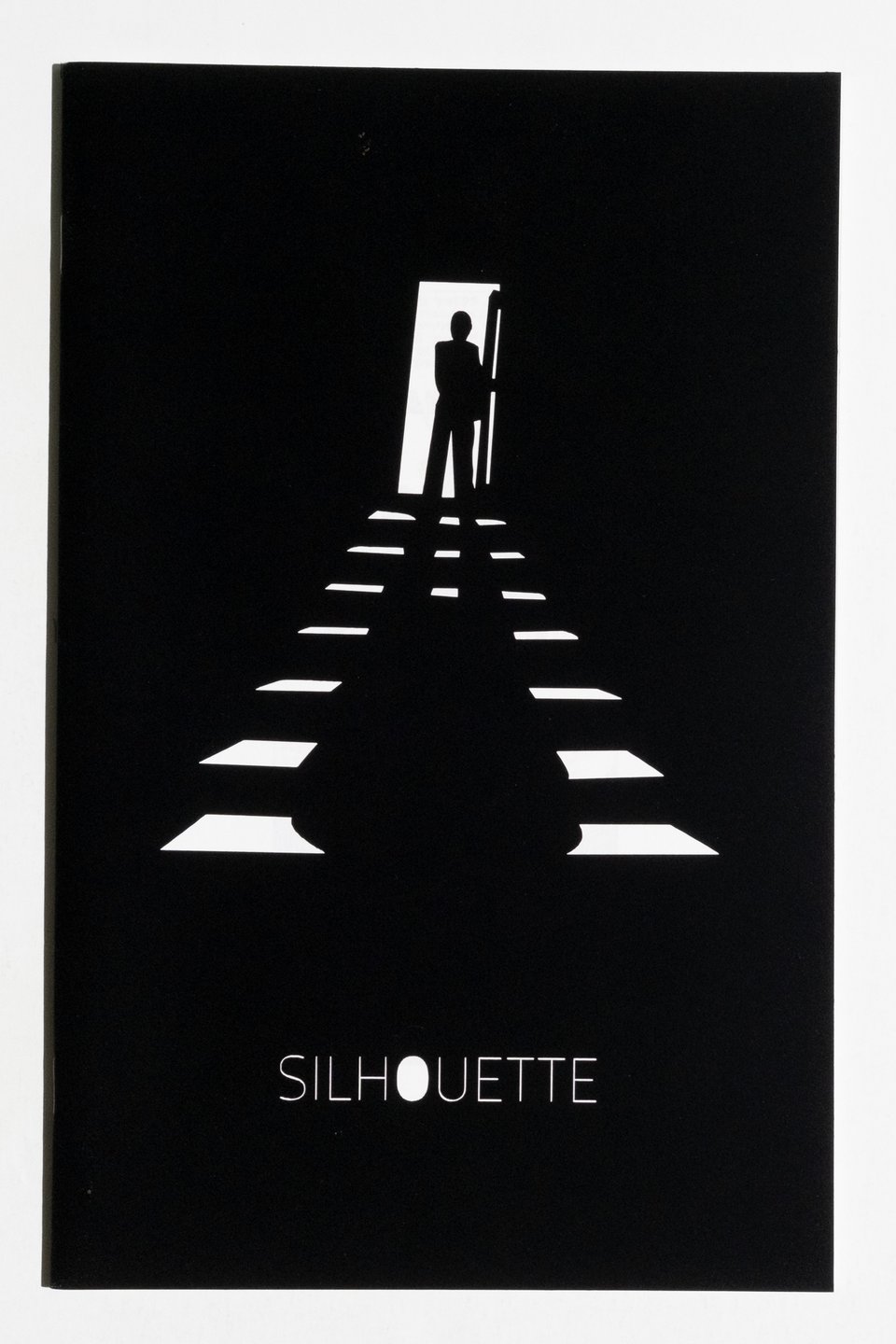 Cover of Silhouette. The image is adapted from a silhouette drawn by Richard Corben of a figure standing out the top of a staircase. However, the cover is simply black paper that has been lasercut to reveal all of the highlight areas of the image by placing it on top of a white piece of paper