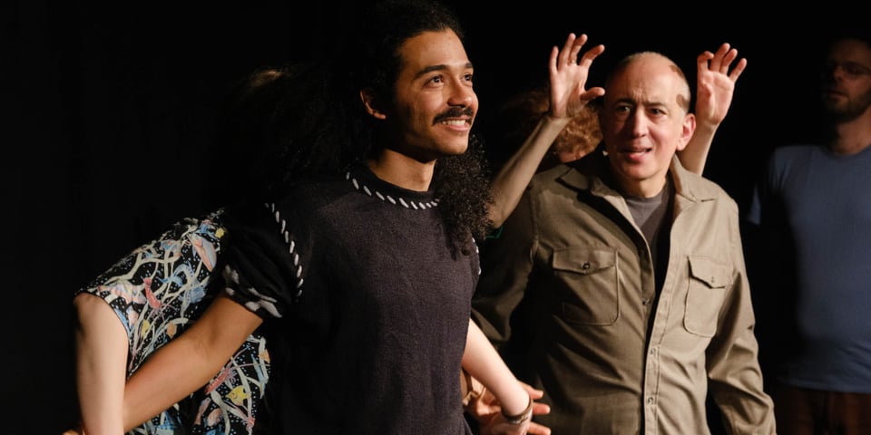 A cohort of improvisers in a physical theatre scene.