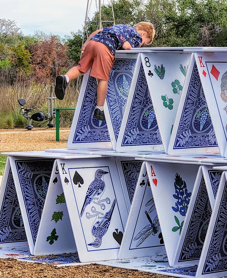 Child peering over a house of cards installation at a playground