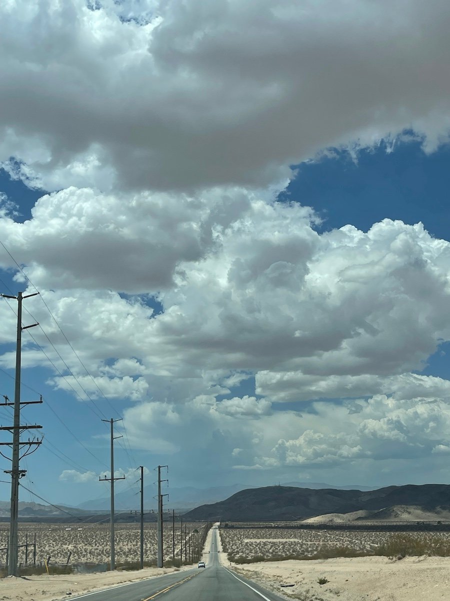a road in the desert, blue skies with lots of clouds