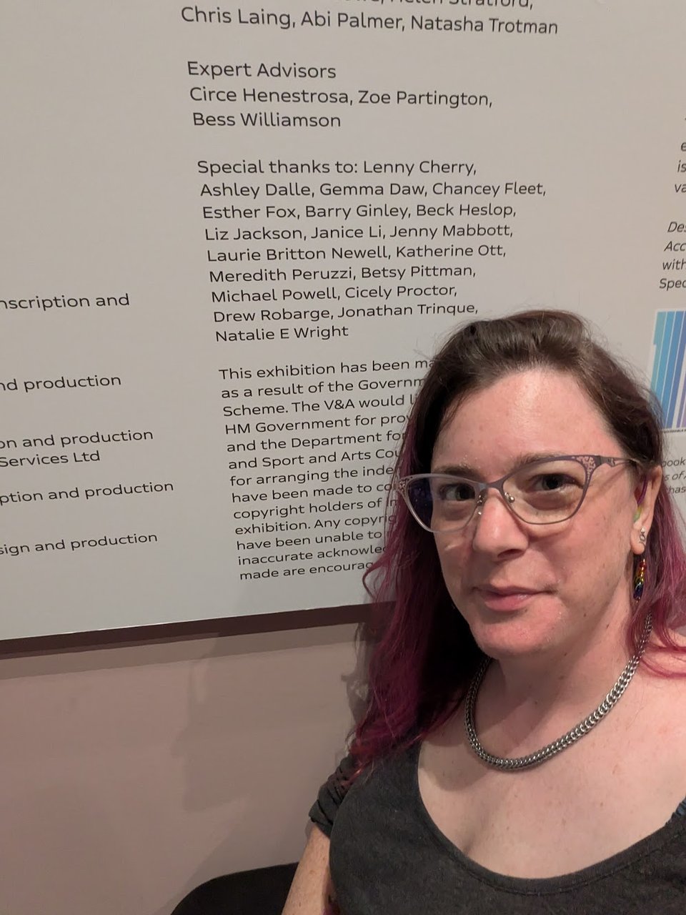 Meredith crouches in front of an acknowledgments panel, where her name is posted with those of 18 other people under Special Thanks.