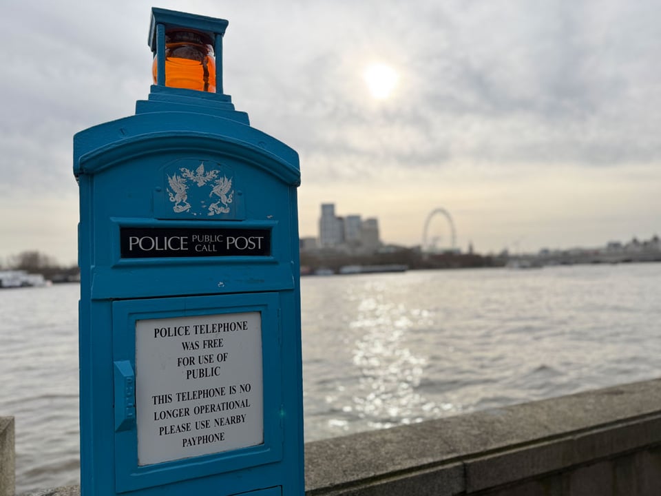 A blue Police Box is in disuse, but remains. A sign tells people to use the nearby payphone, which isn't in use either.