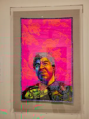 A mixed media portrait of Octavia Butler in psychedelic colors. It is primarily quilted but also features glitter and buttons.