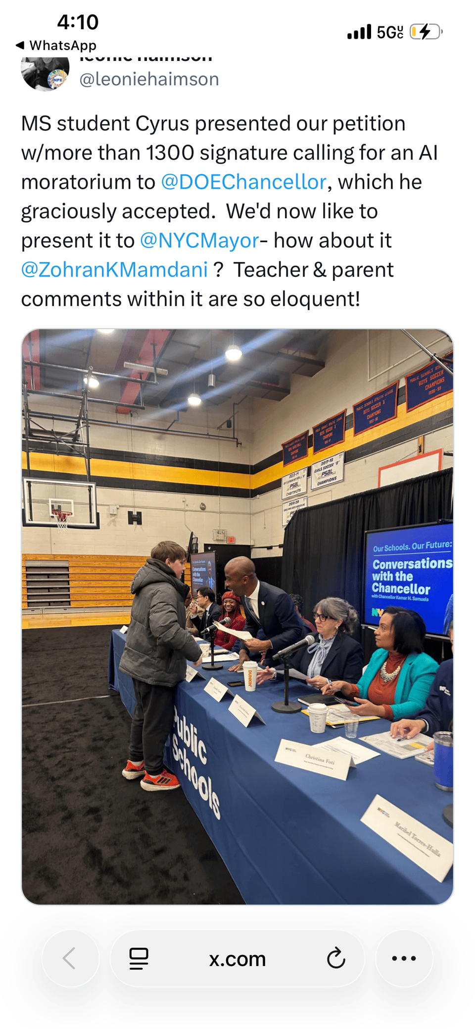 A picture from Twitter of a boy handing the petition to the chancellor who is sitting at a table