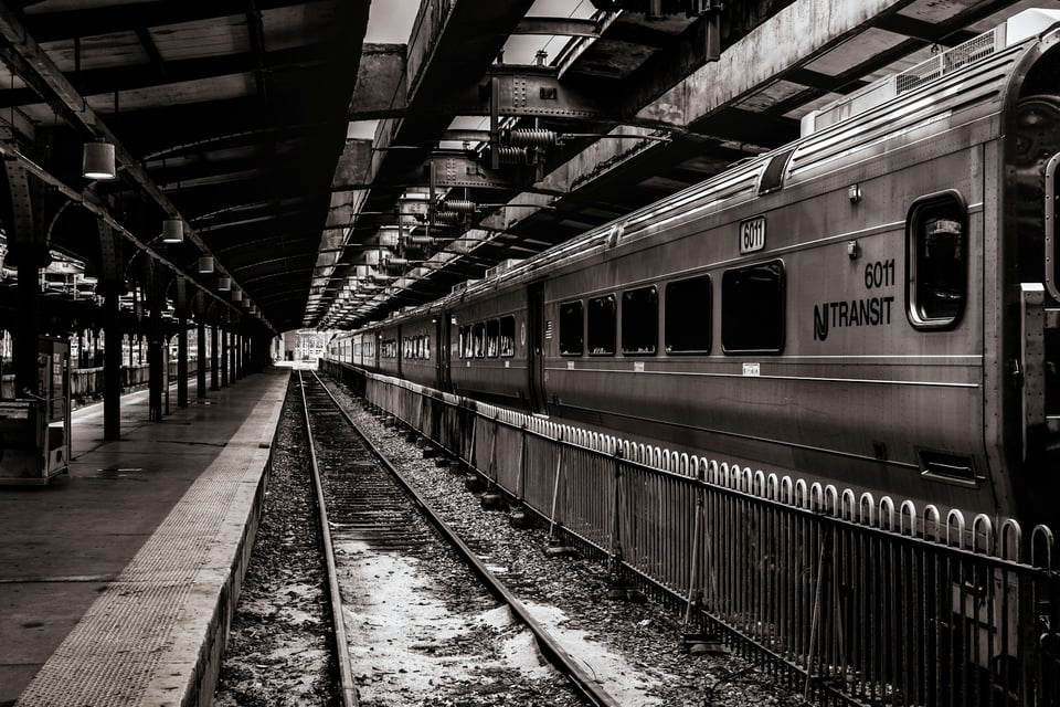Black and white photo of an empty snowy track and empty platform with a NJ Transit train stopped on the opposite track
