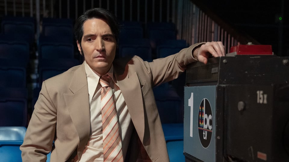 A scene of Late Night with the Devil. The protagonist lean on a TV camera.