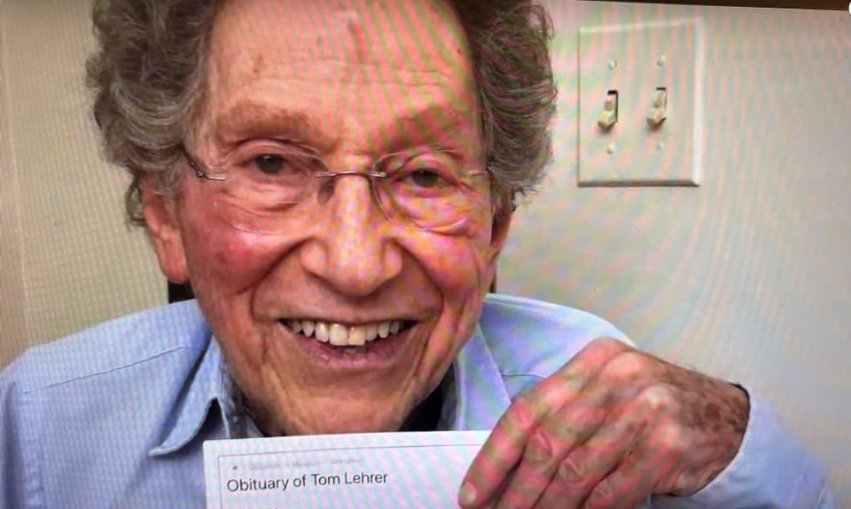 Tom Lehrer holds up a page with the headline “Obituary of Tom Lehrer.”