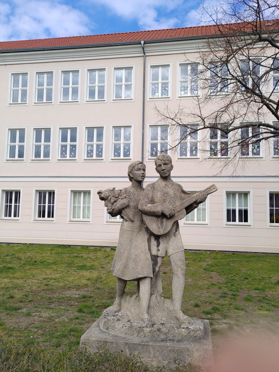 Etwa lebensgroße Skulptur im Stil des sozialistischen Realismus. Ein Junge mit Gitarre und ein Mädchen mit Blumenstrauß.