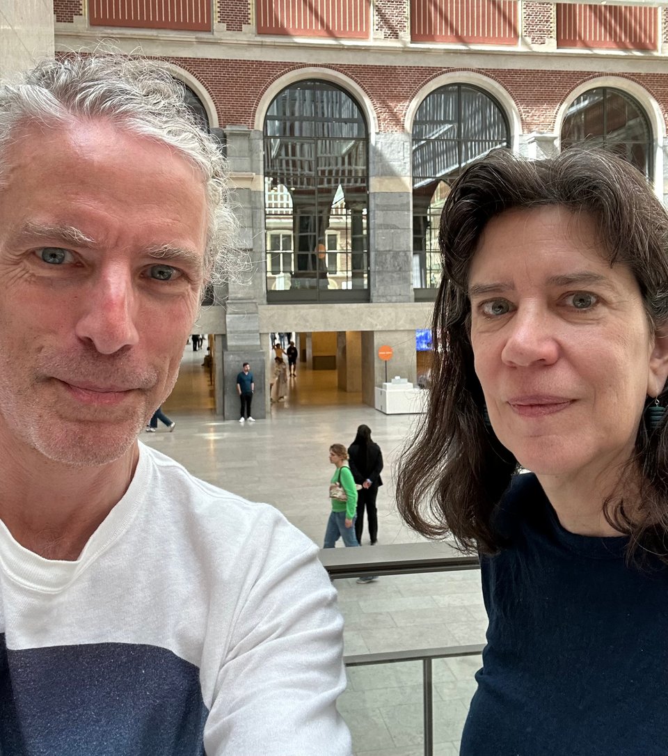 photo of white man (left) and white woman (right) in the cafe of the Rijksmuseum in Amsterdam. They're both trying to smile.