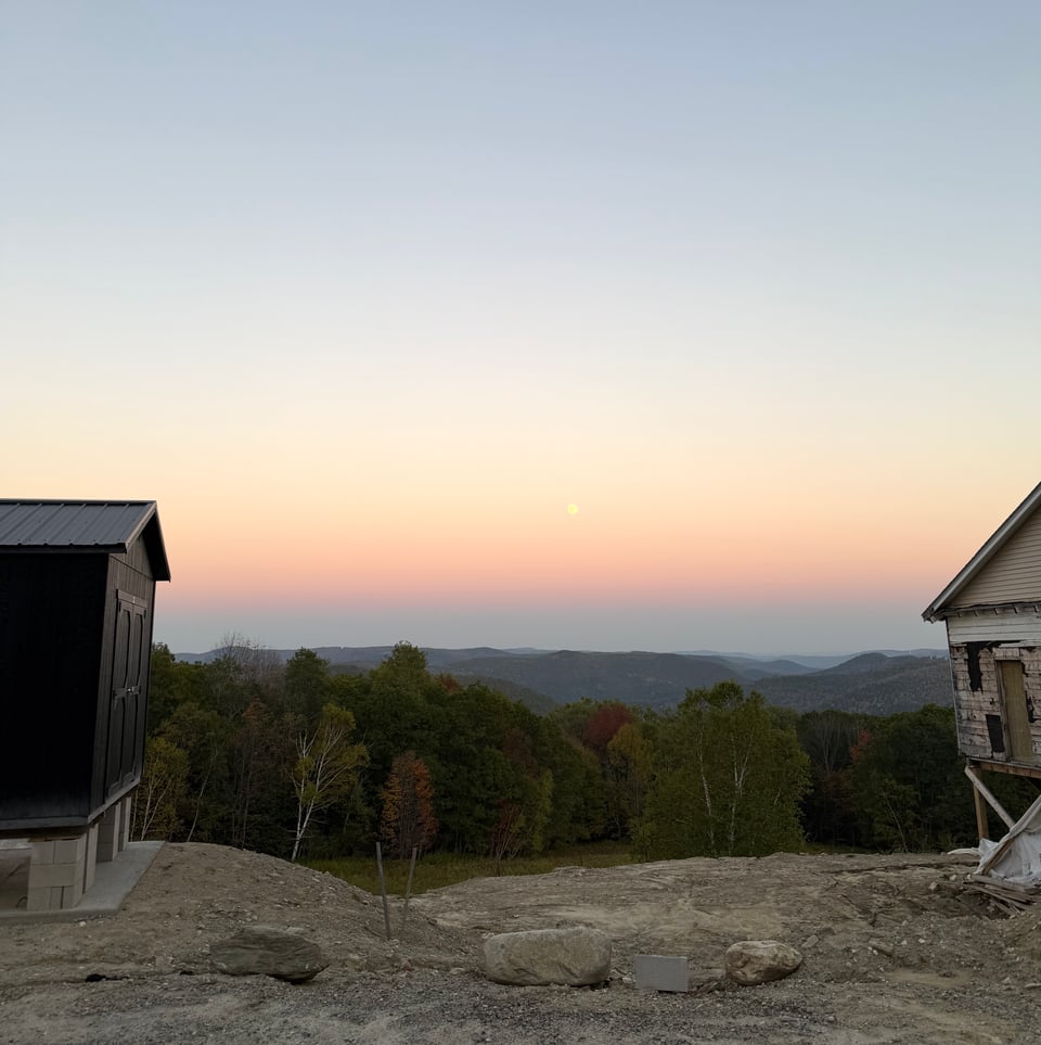 the moon in the sky on a beautiful evening, two unfinished buildings in the foreground