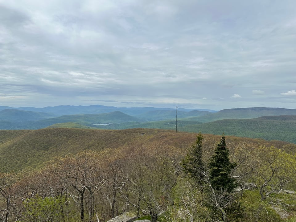 Photo of tree-covered mountains, with a cell tower and a ruined building in the distance