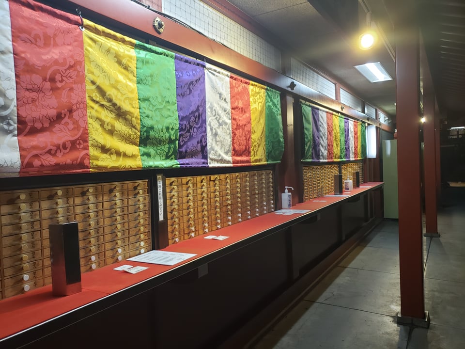 An omikuji station with bright rainbow flags.
