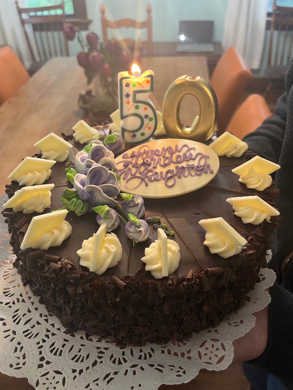 A picture of a beautiful chocolate cake with two candles, a 5 and an 0. There is icing spelling out Happy Birthday, Leighton, except the word birthday is kind of illegible.