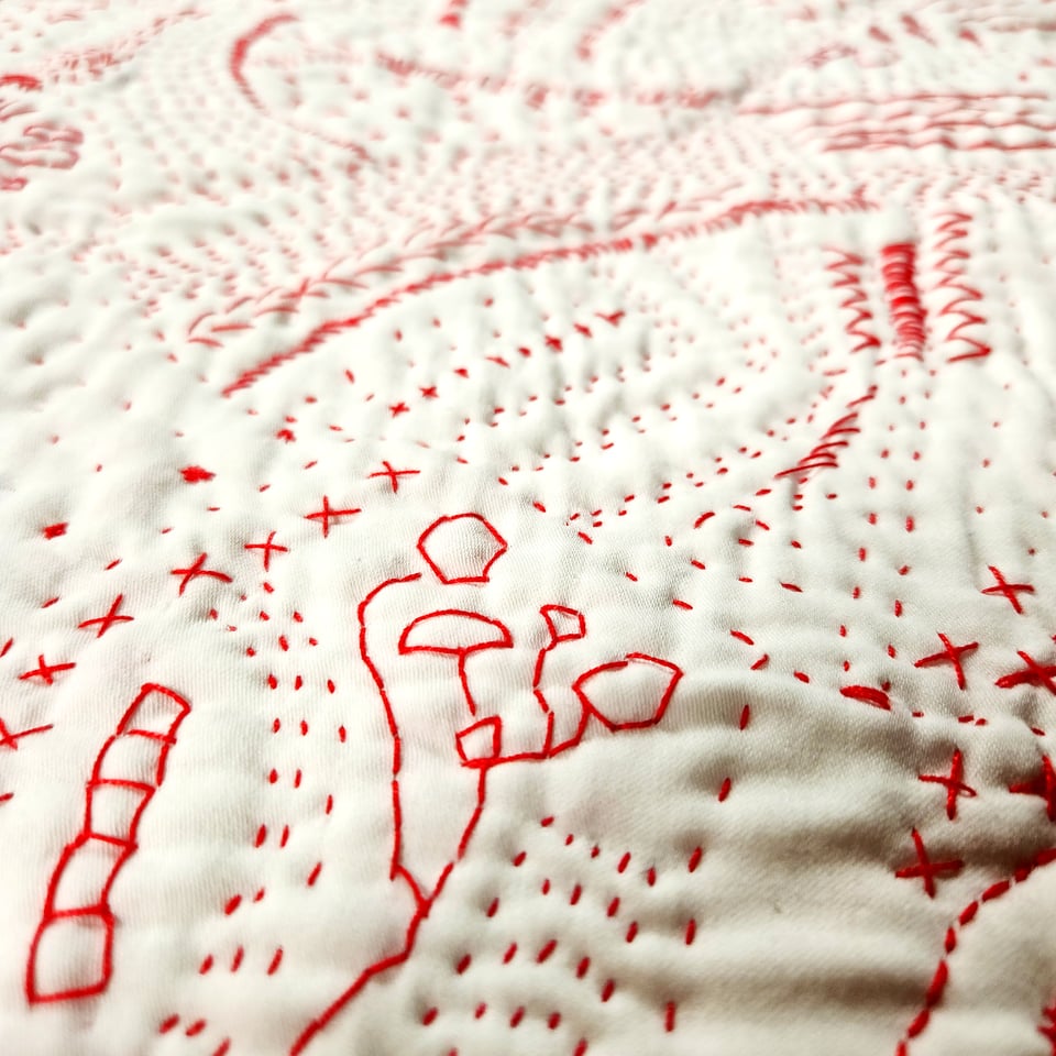Detail of Red Map, a hand stitched quilt by Sarah Atlee. Red thread on white pillowcase, 2025.