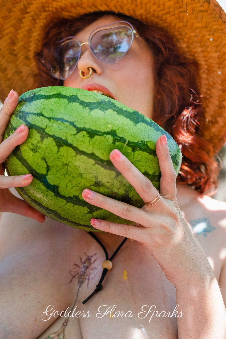 Flora holding a watermelon and licking it, juice pouring down her chest