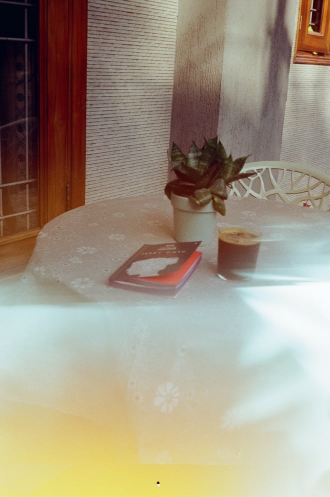 Blurry photo of a book and iced coffee on a table, shot on film