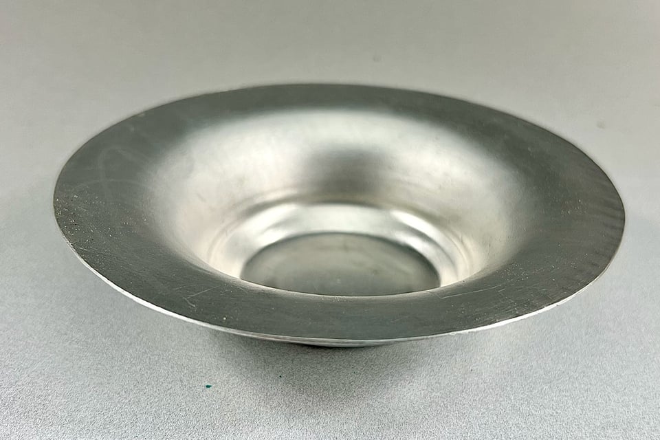 An aluminum bowl with a flat bottom and a wide rim