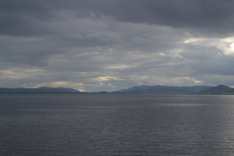 Open water with hills on the far side, under truly threatening skies, shading from gray to black.