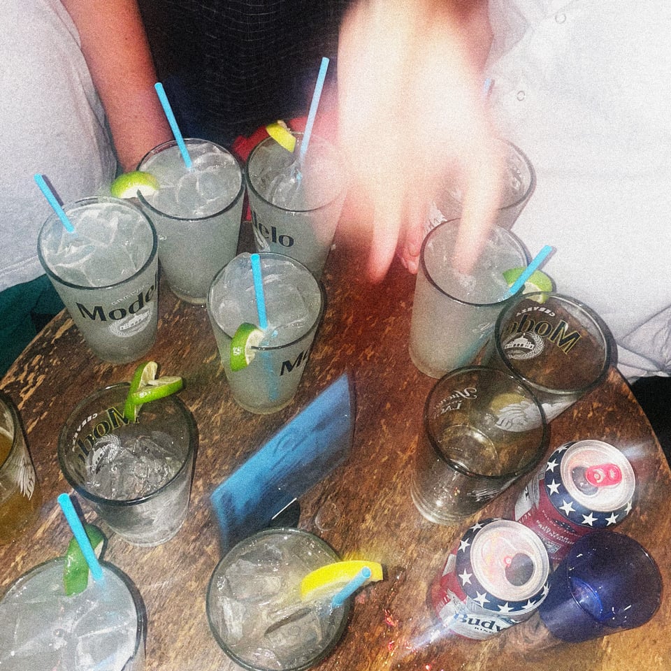 a blurry table full of pint glass margaritas on a sweaty friday night