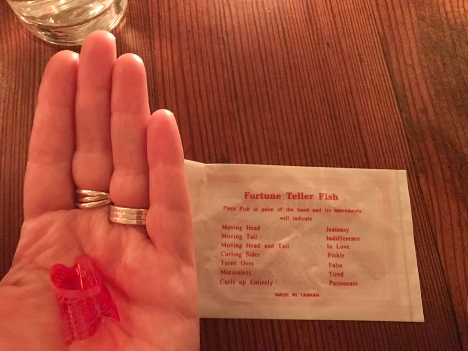 palm holding cellophane fortune teller fish next to description of how it works at the Mermaid Inn, New York City