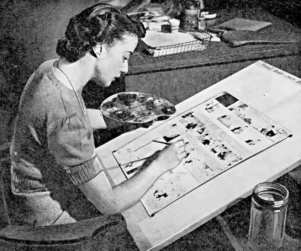 Woman with color ink palette in hand using a brush to draw colors onto a large-format (full page) comic strip proof on a drawing board to indicate colors for engraving