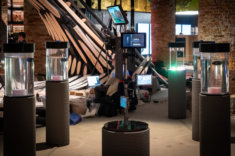 Four cylinders of water surround a set of small screens on a stalk